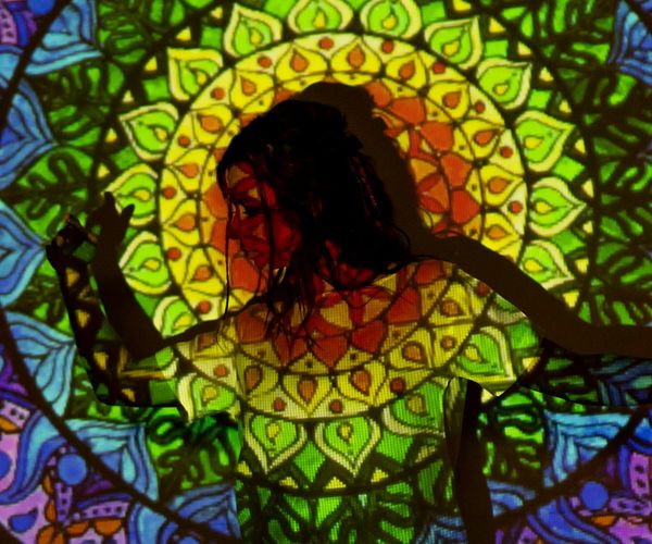 Silhouette of a woman stretching against a bright, abstract background.
